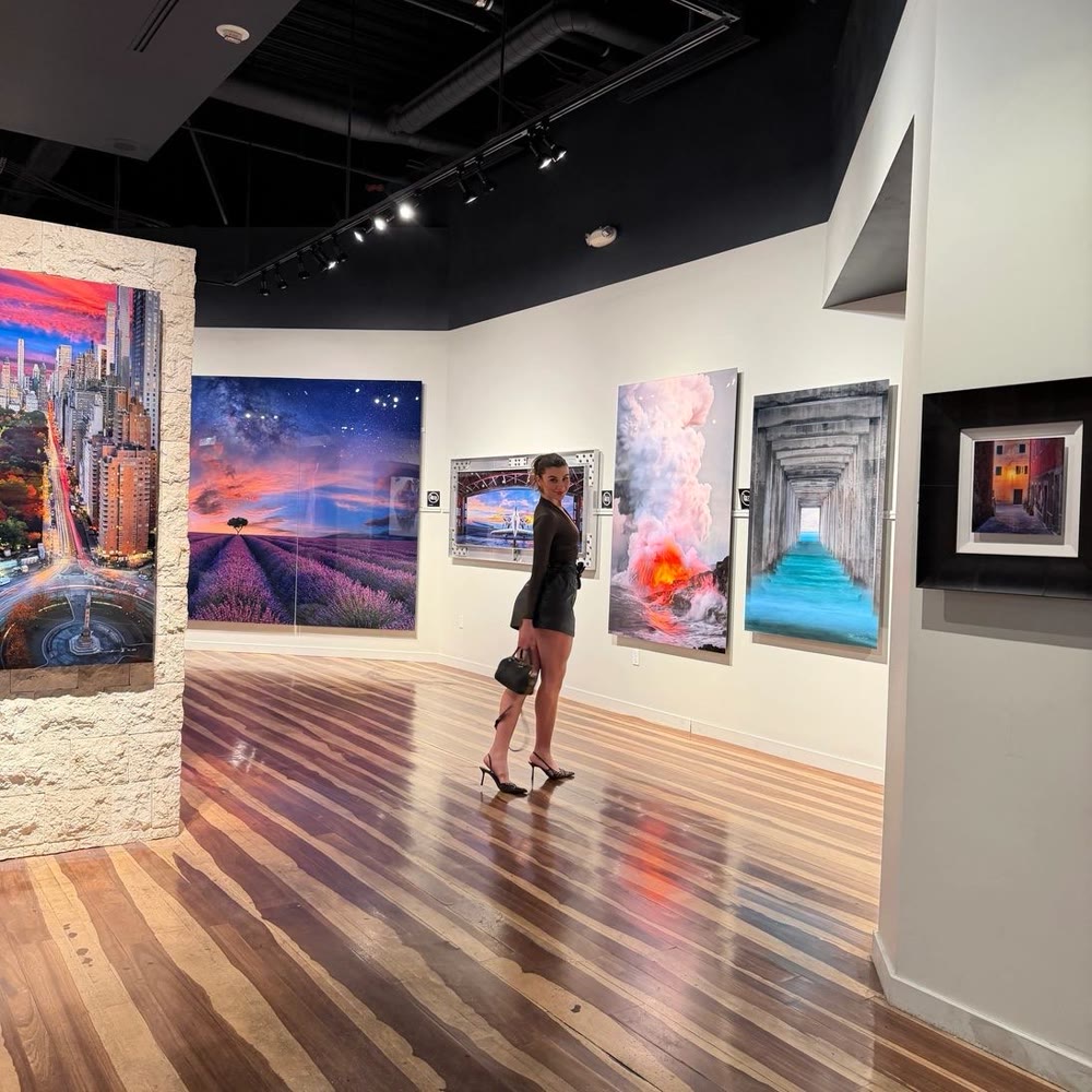 Jade Rosenblum in a black dress at an art gallery, looking back at the camera